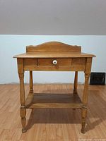 Front view of wooden washstand showing drawer with ceramic knob and lower shelf