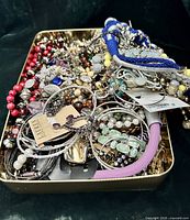 Top view of tin filled with assorted jewelry pieces