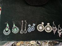 Five pairs of assorted chandelier/dangle earrings on dark fabric
