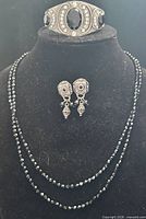 Full set showing bracelet on stand, necklace draped on bust, earrings centered
