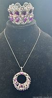 Necklace with pendant displayed beside matching rhinestone cuff bracelet