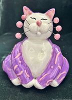 Front view of purple, pink and white ceramic cat figurine