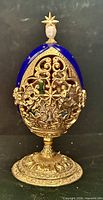 Closed egg on pedestal showing cobalt enamel and gilt metal exterior