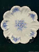 Full view of scalloped floral porcelain plate on stand