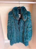 Front view of blue faux fur coat on hanger