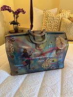 Front view of refurbished doctor’s bag showing handle, clasp, painted graphics and text