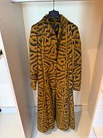 Front view of long yellow and black patterned coat on hanger