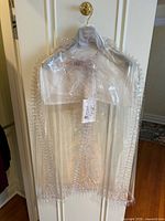 Front view of cape in garment bag with tag