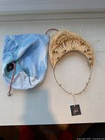 Necklace with raffia fringe and bead accents alongside Rosantica dust bag, hangtag visible