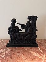 front view of cast iron doorstop showing two classical figures and full base