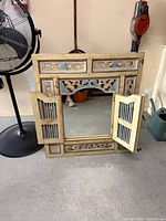 Front view of rectangular carved mirror with shutters open