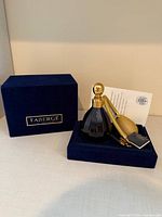 Perfume bottle on velvet base with bulb atomizer, certificate and box lid visible