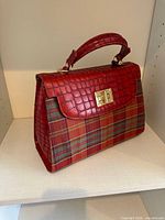 Front view showing crocodile-embossed leather flap, plaid panel, gold-tone turn lock