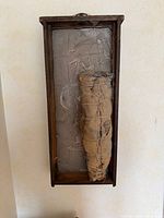 Front view of framed shadow box with burlap-wrapped object and chalk markings