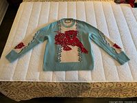 Front view of Gucci sweater laid flat on bed