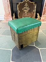 Front angled view showing green leather seat, hammered metal sides, decorative embossing