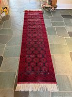 Full view of Afghan Bokhara runner showing red field, gul motifs, and fringe