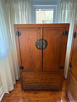 Front view showing paneled doors, brass moon lock and carved apron