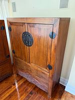 Front view of elmwood cabinet showing doors, brass hardware, carved apron