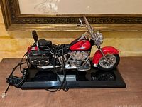 Left front view of motorcycle telephone on base showing chrome engine, red fender, saddlebags, handset cord