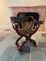 Front angled view of carved wood and leather Savonarola armchair