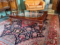 Angled view of coffee table showing glass inset, carved apron, cabriole legs