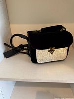 Front view showing black velvet body, silver embossed panel, brass clasp