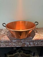 Top-angle view of copper jam pan showing cast-iron handles and interior