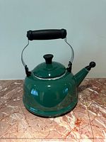 Front view of green Le Creuset kettle on marble surface