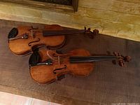 Both violins side by side showing fronts, bodies, fingerboards and chin rests