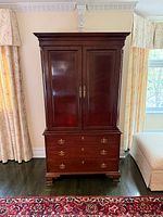 Front view showing two doors, three drawers, brass-tone hardware, crown moulding, bracket feet
