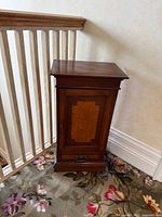 Angled view showing cabinet form, inlaid door panel, drawer hardware