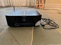 Front angled view of receiver, antenna, remote, power cord visible