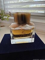 Front view of perfume bottle showing liquid level, cap, ribbon and label