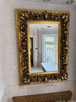 Full view of mirror on wall showing ornate gilt frame and reflection