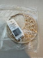 Front view of pair of crocheted hoop earrings in plastic bag with tag