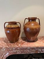 Pair of terracotta amphora vessels on marble surface