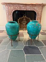 Both urns on stands in front of fireplace