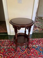 Front view of mahogany round accent table showing top, apron, supports and lower shelf