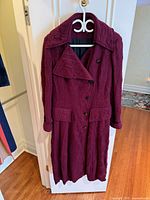 Front view of reddish-purple wool long coat on hanger