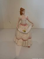 Front view of figurine showing full gown, scarf and flower detail
