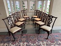 Eight mahogany Chippendale-style chairs arranged in semicircle showing fronts, backs, upholstery, and leg carving