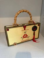 Front view of purse showing Montecristo logo, bamboo handle, red clasp and charm