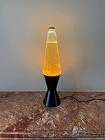 Full view of illuminated lava lamp on marble surface