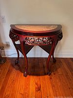 Front view of demilune console table showing marble top and carved apron