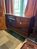 Front view of walnut Saba stereo console showing tuner, door, speaker grill, legs