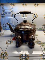 Front view of hammered copper kettle with wooden handle and two mills