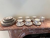 Full service laid out: stacked plates, cups, saucers, sugar bowl