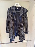 Full front view of navy open-knit cardigan hanging on hanger