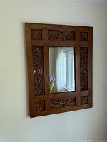 Front view of carved wood mirror on wall